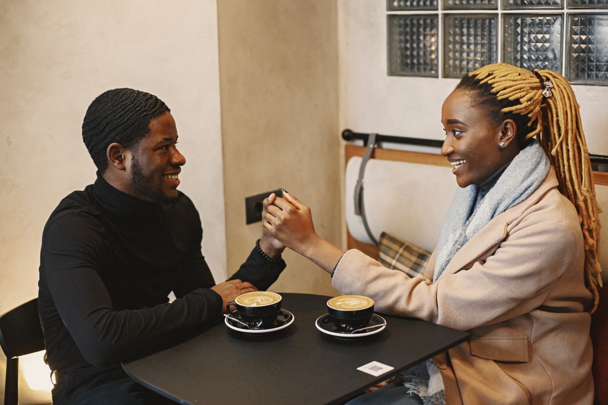 Un couple se tient la main autour d’un café