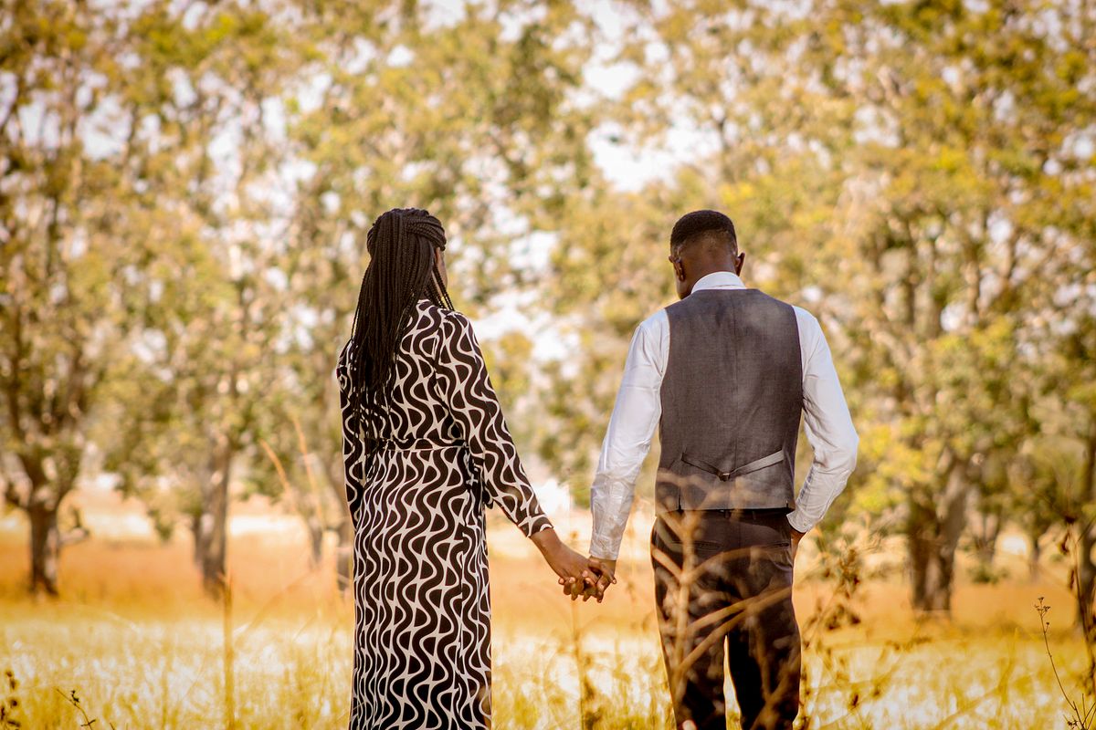 Una pareja camina de la mano bajo los árboles